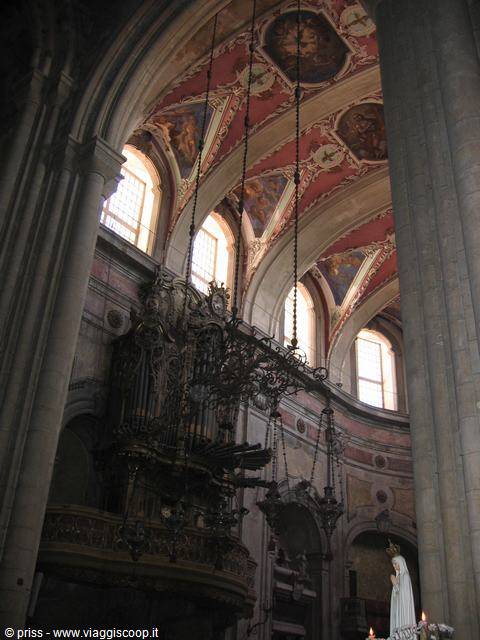 Baroque organ under red and gold frescoed vault, light from basilica windows