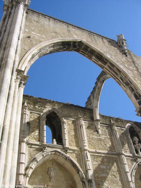 Gothic stone arches of the Carmo Convent in Lisbon against blue sky