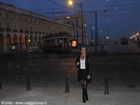 Woman in black jacket on Praça do Comércio cobblestones, tram and yellow building
