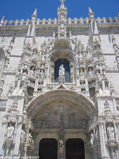 Carved stone facade of the Jerónimos Monastery, saints' statues under blue sky