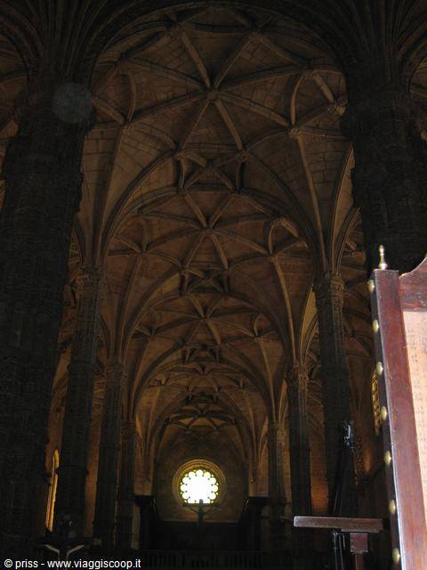 Stone fan vaults and a glowing rose window inside the Jerónimos Monastery, Lisbon