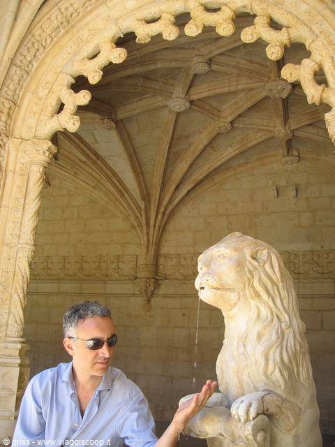 Man touches water from the lion fountain in the Jerónimos cloister, Lisbon