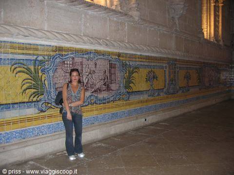 Woman beside blue and yellow azulejo tiles, warmly lit church wall