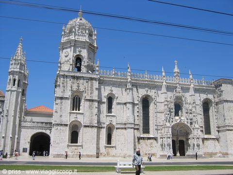 Jerónimos Monastery in Lisbon, carved pale stone, tourists walking under blue sky