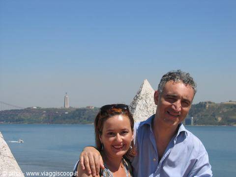 Smiling couple by the Tagus river, Cristo Rei statue in the background, Lisbon