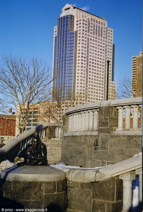 Bronze statue on snowy stone balustrade in front of skyscraper