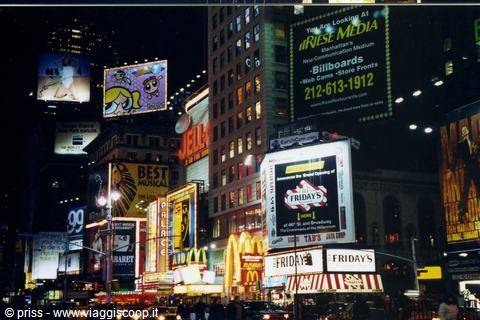 Times Square at night, glowing billboards and neon signs above crowded sidewalks