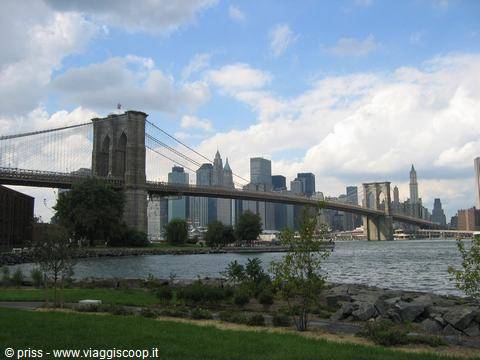 Brooklyn Bridge over the East River with Manhattan skyscrapers under clouds