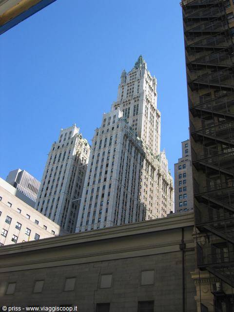 Woolworth Building skyscraper in light stone against blue sky, between buildings