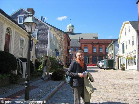 Smiling tourist on a cobblestone street in Nantucket among wooden houses