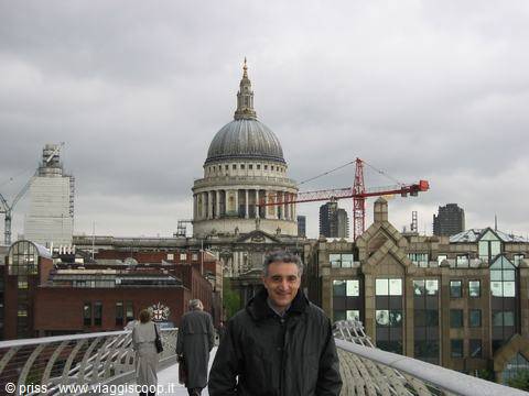 Tourist on the Millennium Bridge with St Paul's dome and cranes