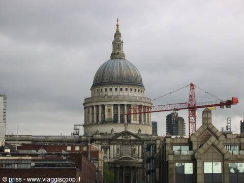St Paul's Cathedral dome in London beside a red crane under grey sky