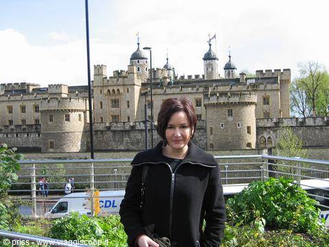 Woman in black jacket in front of the Tower of London, medieval stone walls