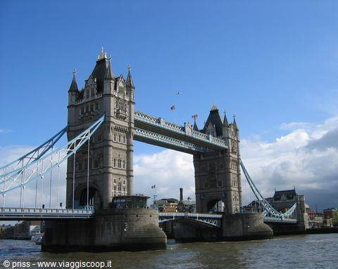 Stone tower with blue suspension bridge over the Thames, cloudy sky above