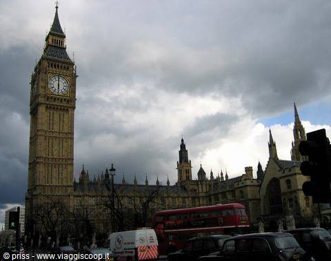 Big Ben and Westminster Palace under grey clouds, red buses in traffic