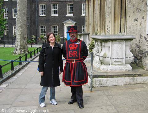 Tourist posing with a Beefeater in red and black uniform at the Tower of London