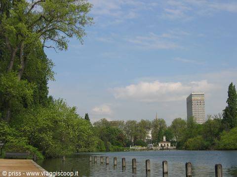 The Serpentine lake in Hyde Park, wooden posts in water, skyscraper behind trees