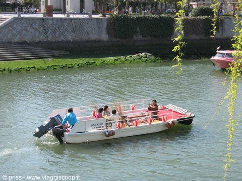 Turisti su una barca bianca solcano il fiume di Hiroshima tra salici