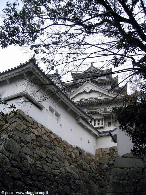 Il castello bianco di Himeji tra rami spogli e mura di pietra