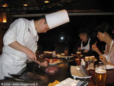 Lo chef del teppanyaki cucina la carne davanti ai clienti