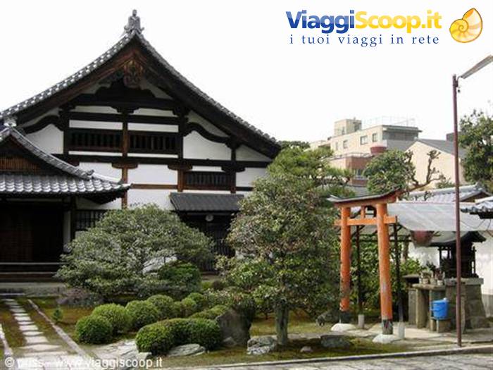 Tempio in legno e piccolo torii vermiglio nel giardino di Kyoto