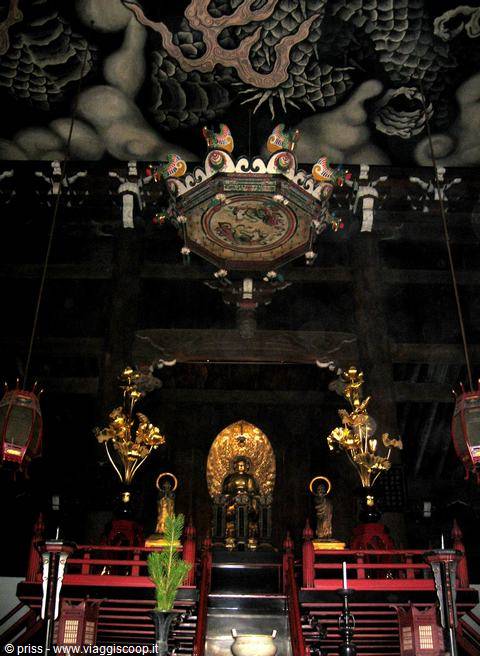 Buddha dorato sotto il soffitto del drago, tempio buio a Kyoto
