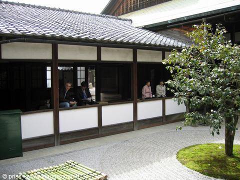 Visitatori seduti in un tempio zen con giardino di sabbia rastrellata a Kyoto