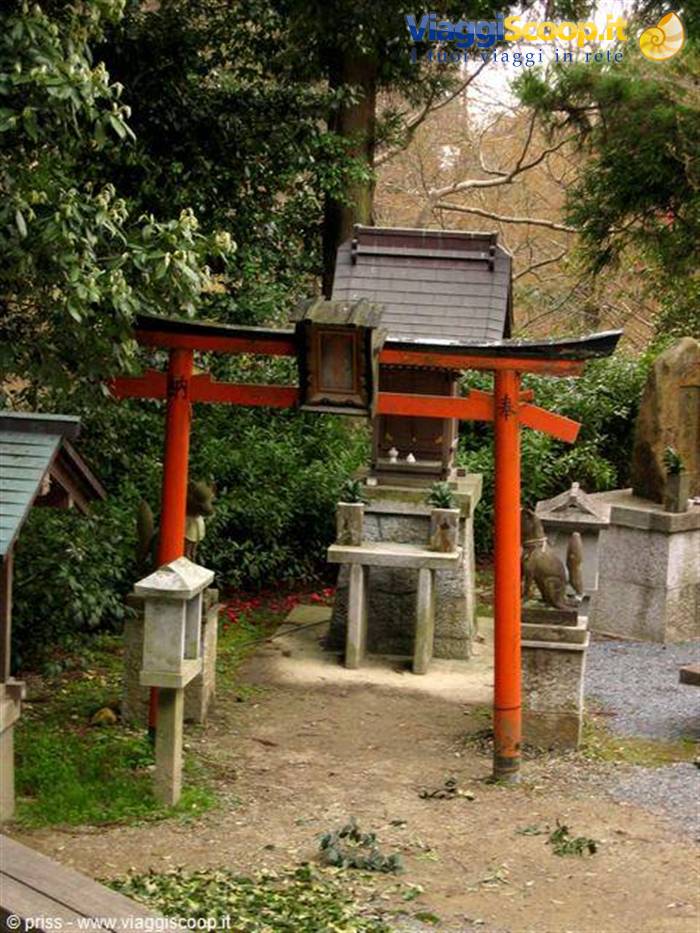 Red torii gates and small stone shrine surrounded by green trees