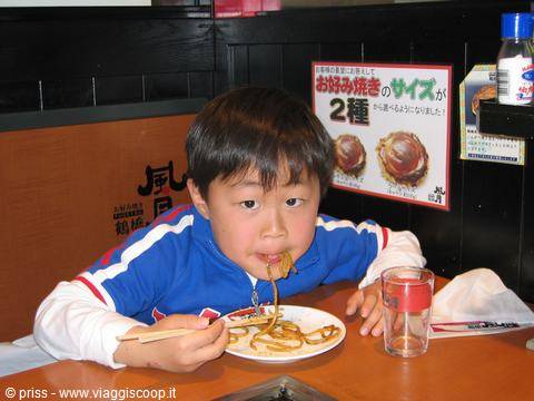 Bambino manga yakisoba con le bacchette in un ristorante di Osaka