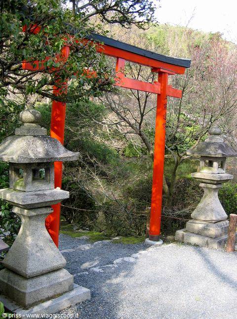 Red torii gate between stone lanterns in a Japanese garden