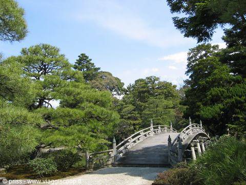 Ponte di pietra incurvato tra pini, giardino Korakuen a Okayama
