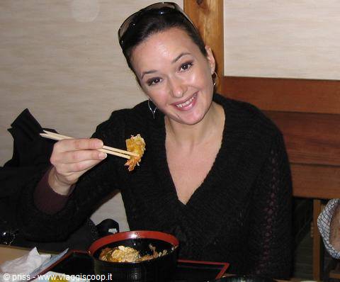 Donna con bacchette mangia tempura in un vassoio lacca, ristorante giapponese