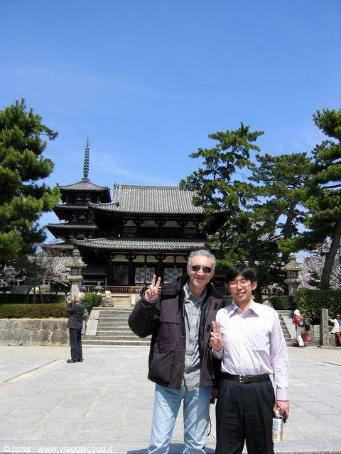 Two men flashing peace signs before the wooden temple pagoda