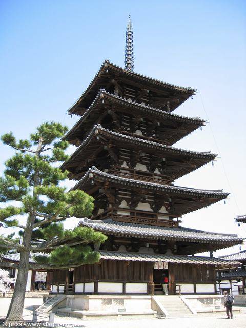 Five-story wooden pagoda of Hōryū-ji temple with pine tree under blue sky
