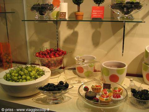 Shop window with glass bowls of fruit, small cakes and candles