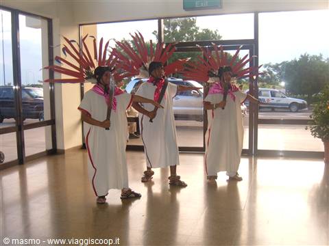 Dancers wearing red feathered headdresses perform a traditional dance in the lobby