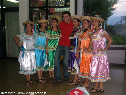 Young man in red shirt with dancers in colorful dresses and straw hats