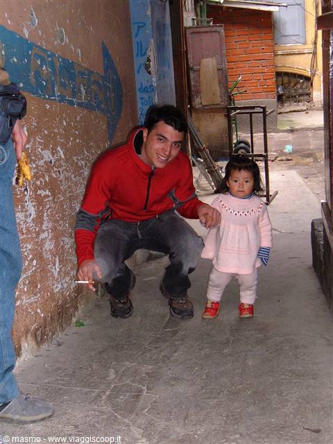 Crouching tourist holds a little girl's hand in an alleyway