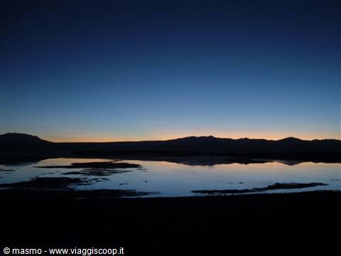 Salt lagoon at dawn, dark mountains reflected in still water