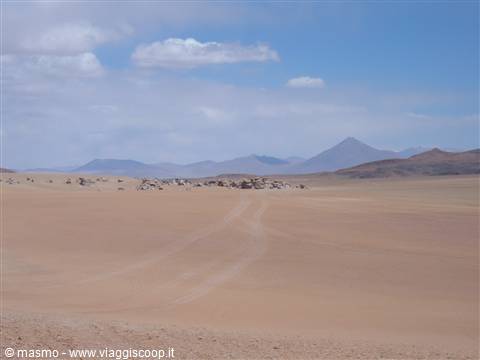 Sandy track across rock formations and volcanic peaks on the Andean altiplano