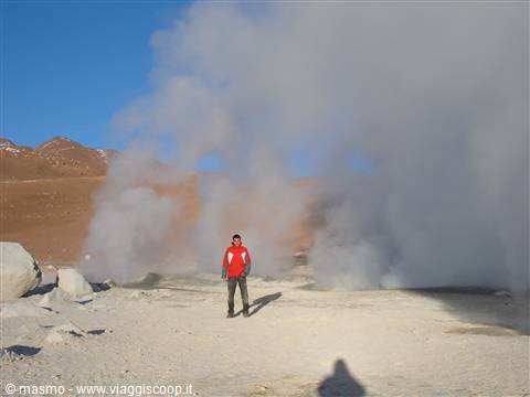 Man in red jacket among steaming fumaroles on high-altitude rocky ground