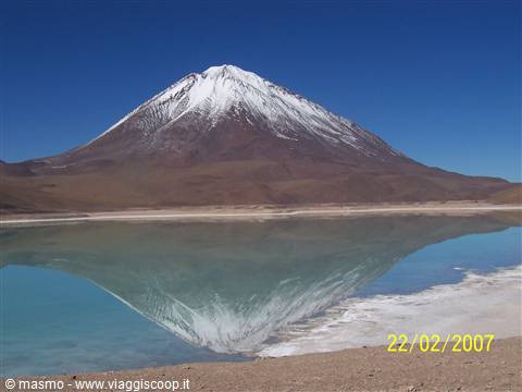 Snow-capped Licancabur volcano reflected in the green lagoon