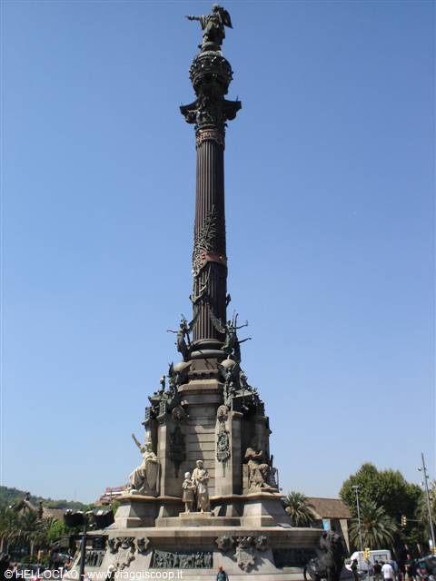Columbus Monument in Barcelona, stone column with bronze statues under blue sky