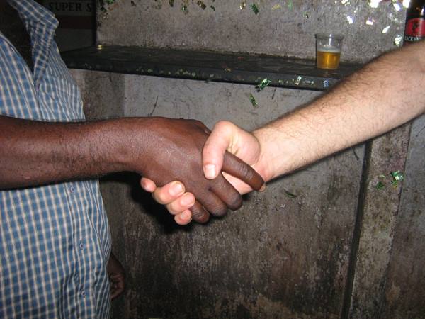 Two hands clasped in a handshake, one dark-skinned and one light-skinned