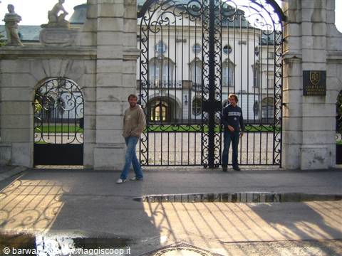 Two people in front of the wrought iron gate of Grassalkovich Palace
