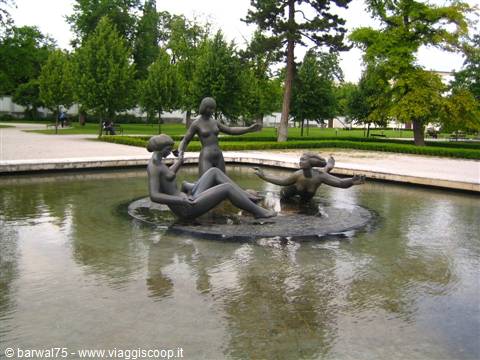 Bronze female statues bathing in a fountain pool in the park