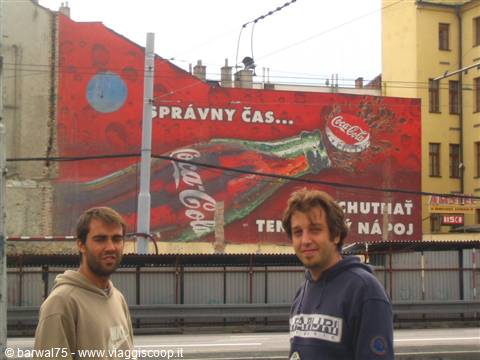 Two young men in front of a large red Coca-Cola mural