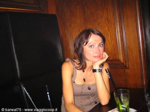 Woman sitting at a pub table with a green drink, wooden walls