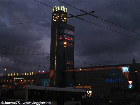 The Rīga station clock tower lit up against the evening sky