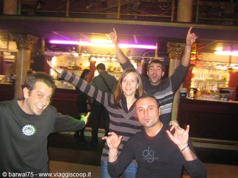 Four cheerful friends posing at a bar with purple lights